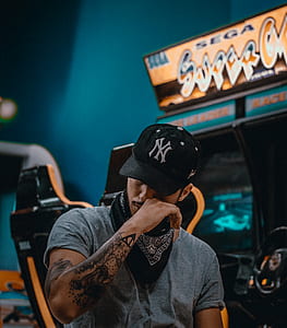 selective focus photography of man wearing black New York Yankees baseball cap at arcade thumbnail