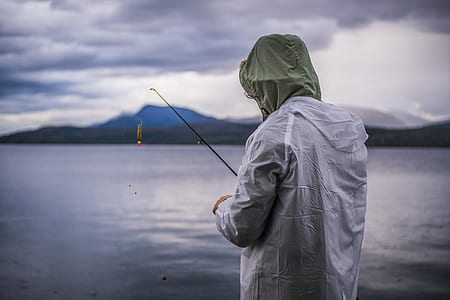 person wearing gray and green hoodie fishing on sea at daytime thumbnail