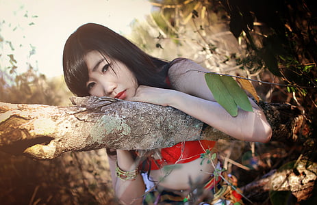 woman in red tube with red lipstick while leaning on tree trunk thumbnail