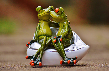 two ceramic frogs sitting on cuddle chair figurine thumbnail