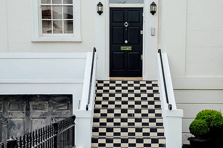 white and black concrete stairs front of black wooden panel door thumbnail