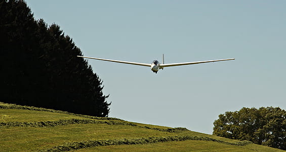 low angle photo of white plane above green grass thumbnail