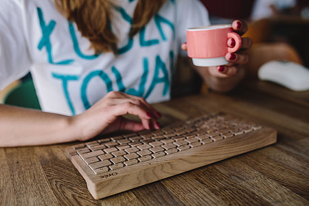 Closeup of female hands typing text on a wireless wooden keyboard thumbnail