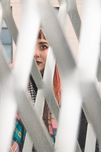 woman standing in front of white link fence at daytime thumbnail