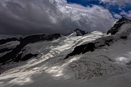 snow covered hills under grey clouds and blue sky thumbnail