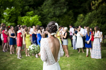 focus photography of woman in bridal gown in front of people on grass lawn during daytime thumbnail