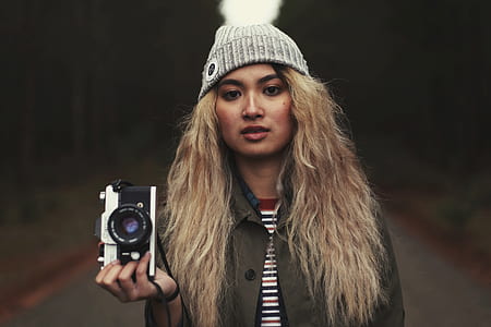 woman standing while holding black and gray MILC camera thumbnail