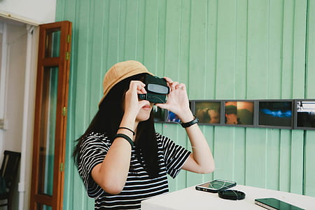 woman in black and white striped top using black camera thumbnail