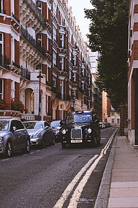 black classic car on grey top road beside high-rise concrete building on daytime thumbnail
