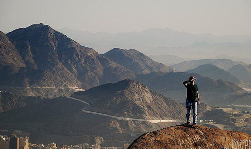 man standing on cliff near city during daytime thumbnail