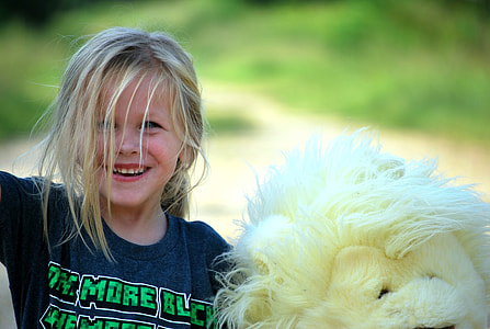 Girl wearing black printed shirt standing beside white lion plush toy thumbnail