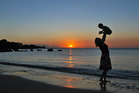 woman carrying baby near seashore thumbnail