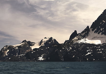 mountain covered by snow beside body of water thumbnail