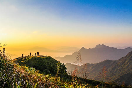 Photo of People Standing on Top of Mountain Near Grasses Facing Mountains during Golden Hours thumbnail