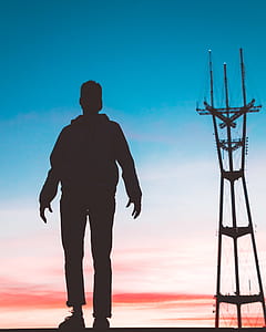 person standing near industrial plant shadow photography during sunset thumbnail