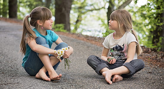 girl holding flowers while sitting on asphalt road during daytime thumbnail