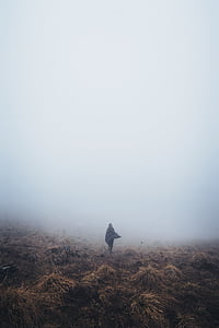 woman standing in middle of field with fog in background thumbnail