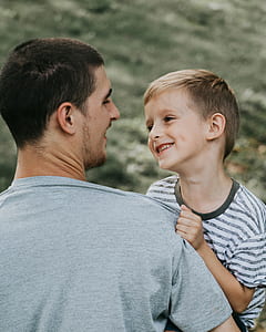 man carrying boy in white and black striped crew-neck T-shirt thumbnail