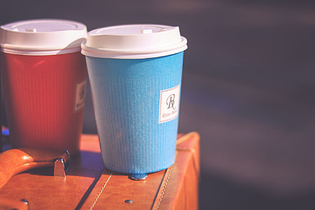 two blue-white-and-red coffee cups on brown leather briefcase thumbnail