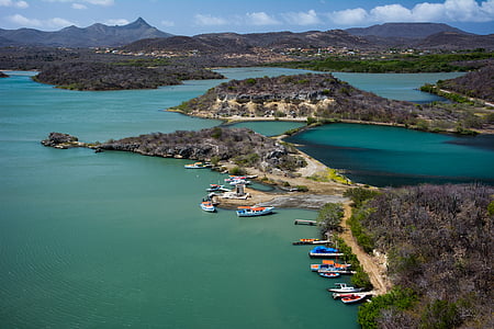 assorted-color boat on blue ocean water surrounded by island taken at daytime thumbnail