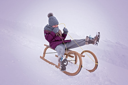 boy on brown sleigh on snow during daytime thumbnail