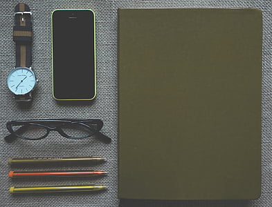 green iPhone 5c, eyeglasses with black frame, black notebook, watch, and three ballpoint pens thumbnail