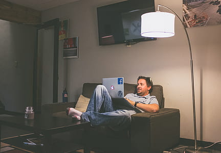 man sitting on black sofa white using laptop thumbnail