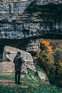 Man Standing in Front of Rock Formation thumbnail