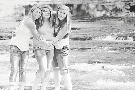 grayscale photography of three standing women beside body of water thumbnail