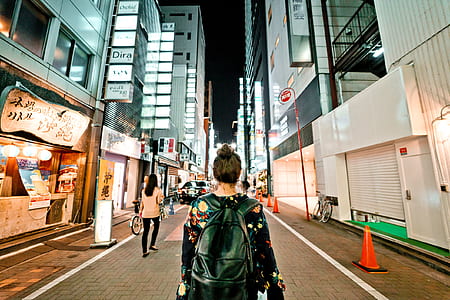 woman standing in the middle of road surrounded by buildings thumbnail