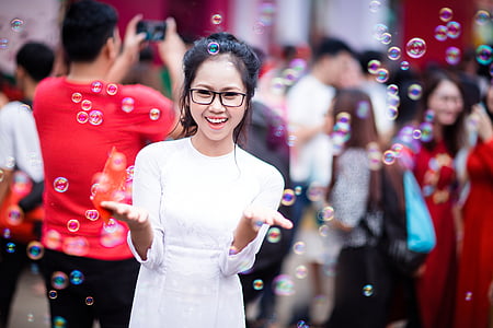 selective focus photo of woman surrounded with bubbles located in the crowd during daytime thumbnail