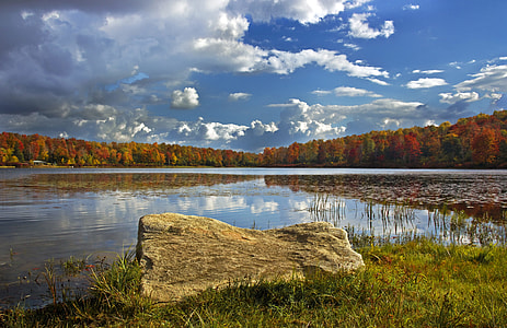 grey rock near small body of water under white and blue sky at daytime thumbnail