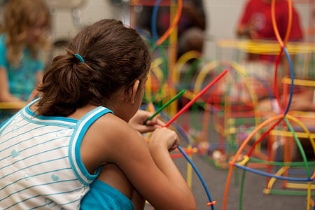 girl in white and blue sleeveless top holding sticks thumbnail