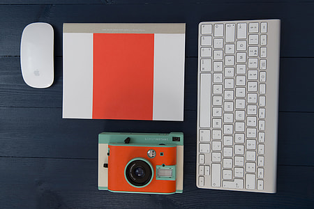 Computer keyboard, mouse, camera and notebook on wood studio desk thumbnail