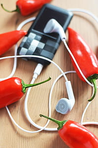 White Earphones Connected to Mp3 Player Surrounded by Red Chili Peppers thumbnail