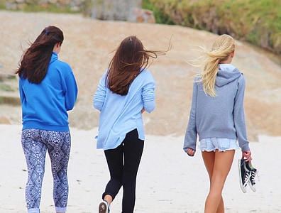 three women walking on seashore during daytime thumbnail