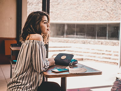 woman wearing white and black striped off-shoulder long-sleeved shirt leaning on brown wooden table thumbnail