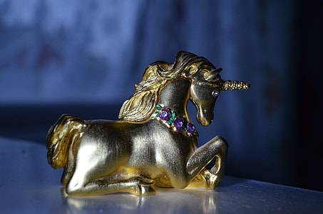 brass figurine of unicorn in closeup photography placed on white table thumbnail