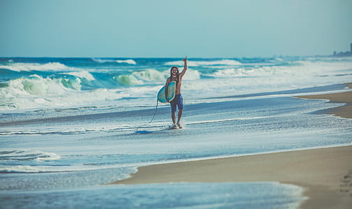 man holding bodyboard walking on seashore thumbnail