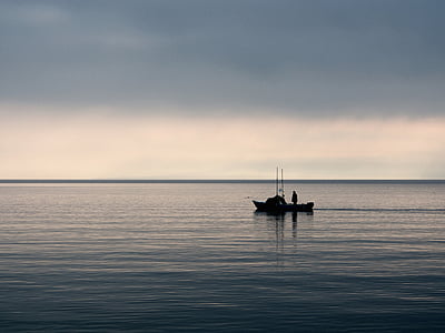 silhouette of boat on blue body of water under cloudy sky thumbnail