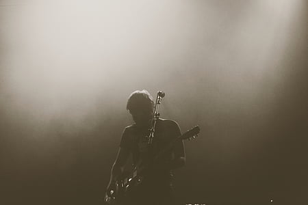 man playing guitar beside a microphone greyscale photo thumbnail