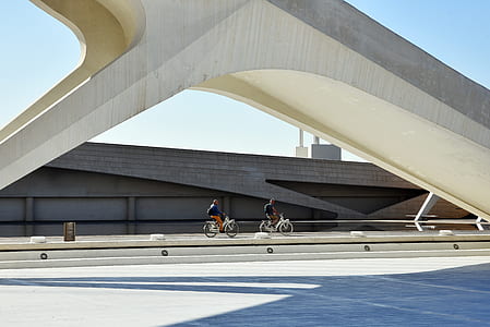 two people riding bikes near wall under blue sky thumbnail