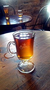 clear glass cup filled with brown liquid on brown wooden table thumbnail