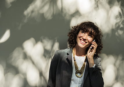 woman in dark-gray notched lapel suit jacket holding smartphone thumbnail