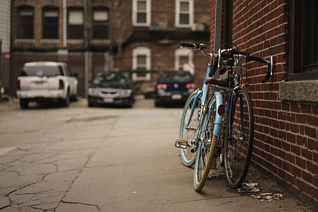 two teal and black leaning on brown brick wall at daytime thumbnail