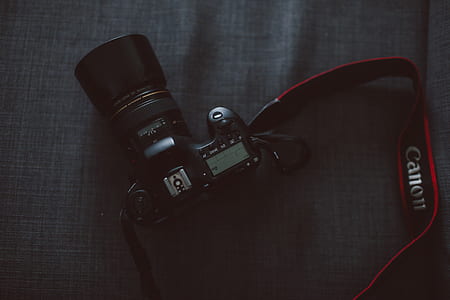 black Canon DSLR camera on gray textile thumbnail