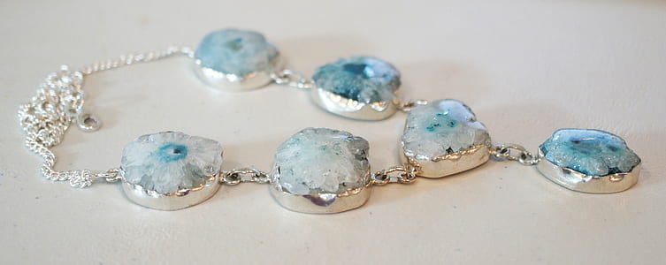 silver-colored teal stone necklace on white board thumbnail