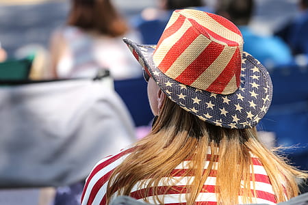 Rear view or seated woman wearing an American Flag hat at a parade. thumbnail