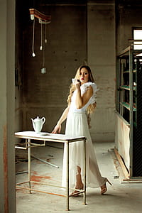 woman drinking tea standing near table with teapot thumbnail