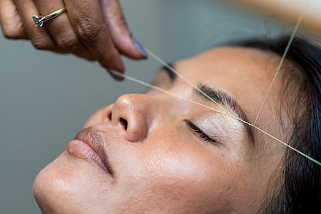 person stitching woman's eyebrow thumbnail